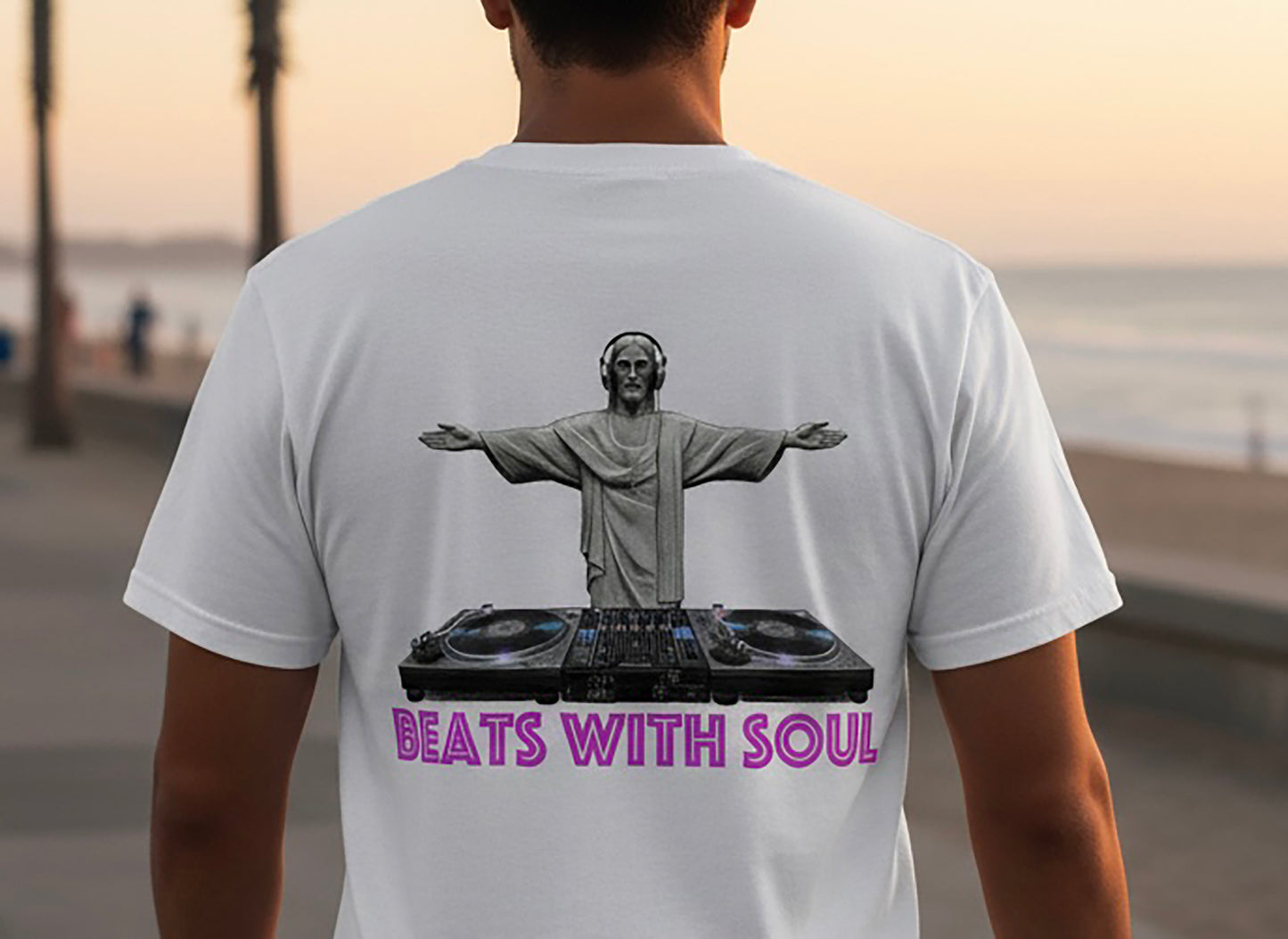 Person wearing a white t-shirt with a graphic of a person on a DJ turntable and 'Beats with Soul' text, standing outdoors.