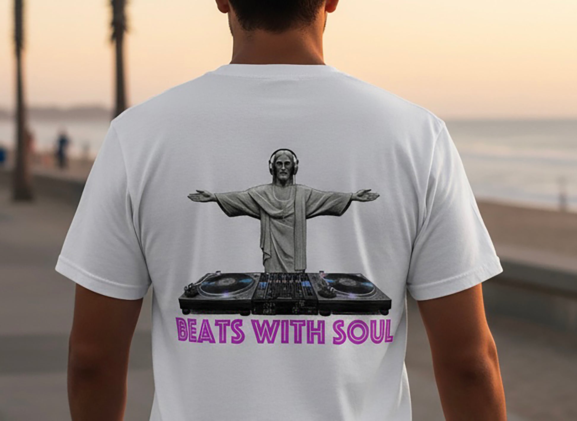 Person wearing a white t-shirt with a graphic of a person on a DJ turntable and 'Beats with Soul' text, standing outdoors.