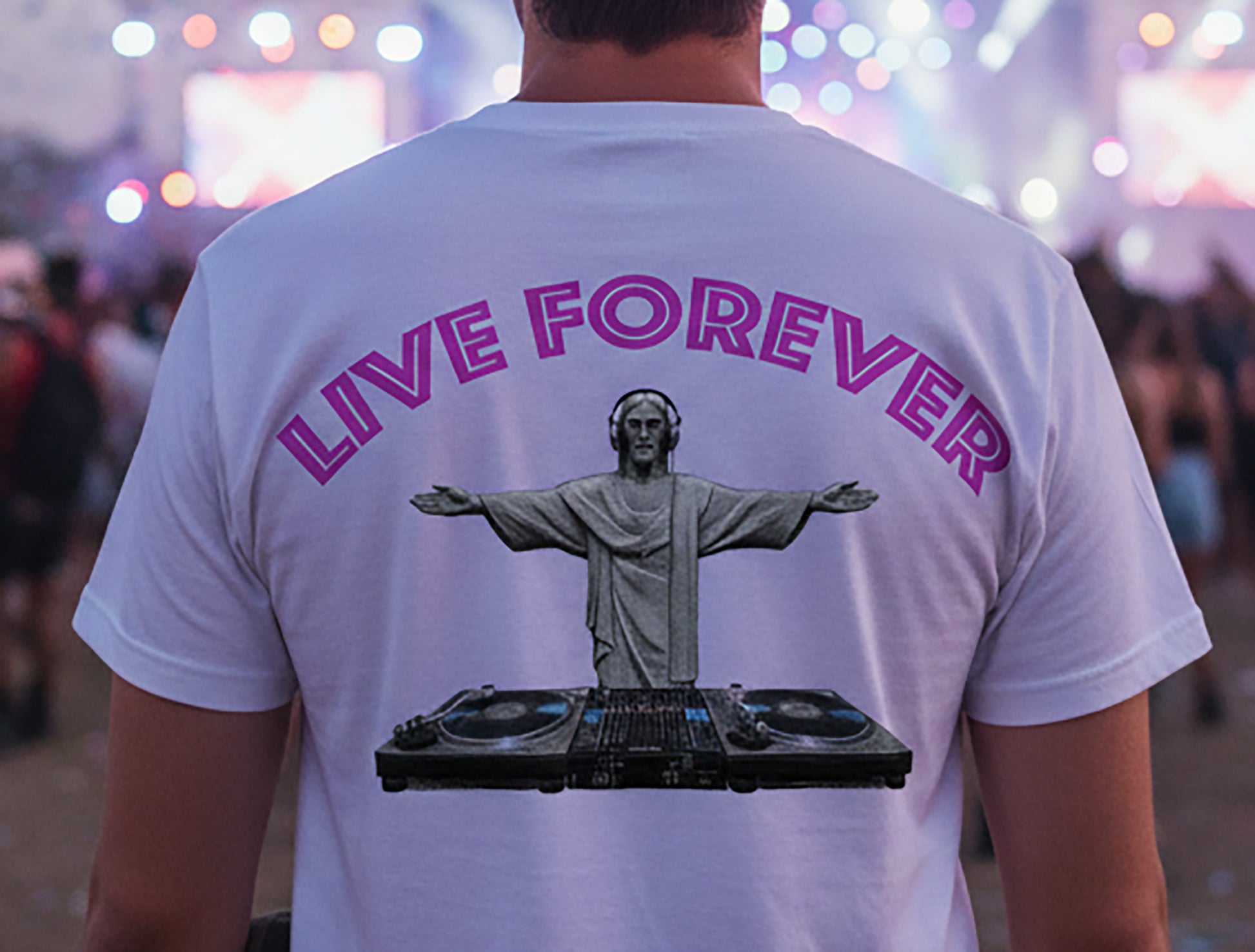 Person wearing a white t-shirt with 'LIVE FOREVER' and a DJ statue graphic, blurred event background