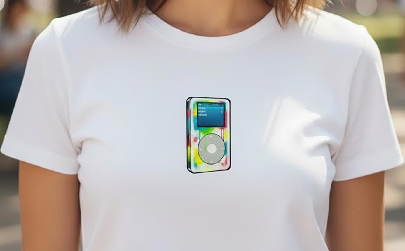 White t-shirt with a colorful iPod graphic on a blurred outdoor background